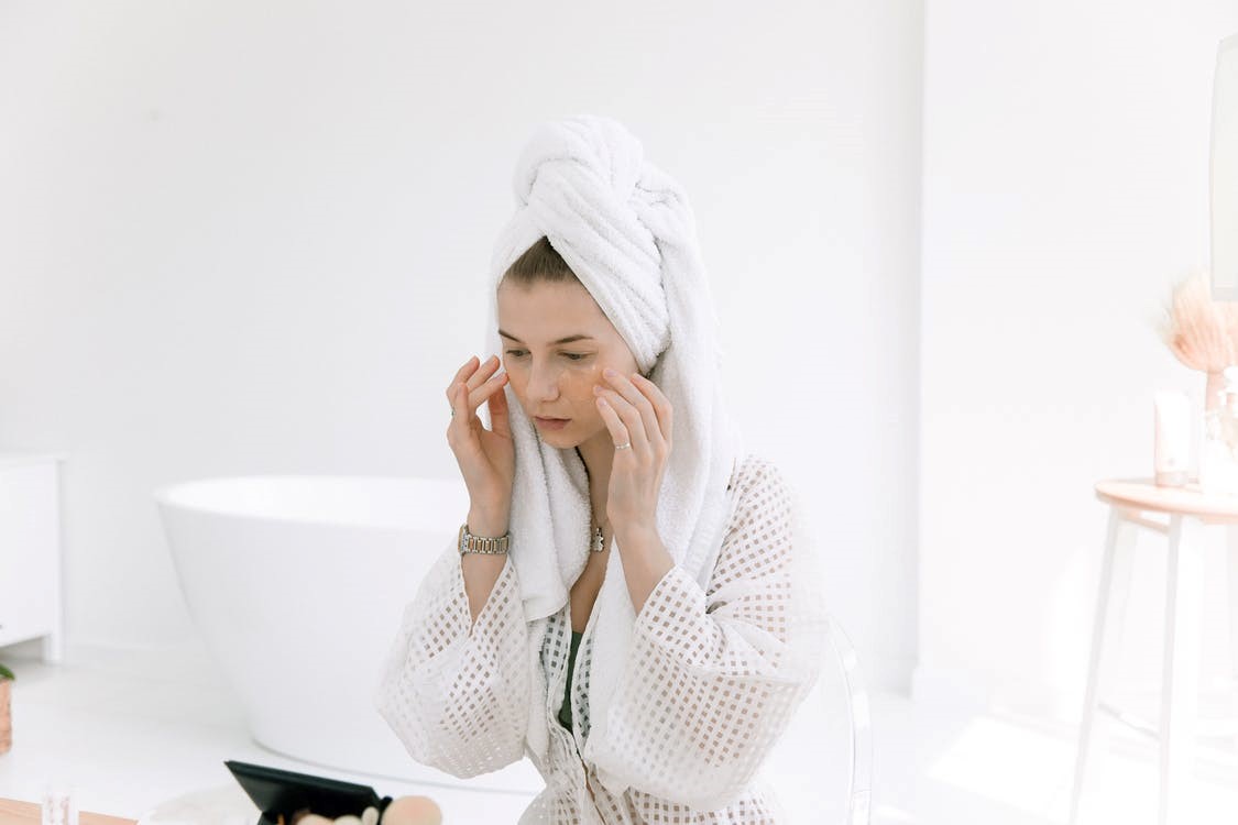 A woman in a bathrobe touching her face