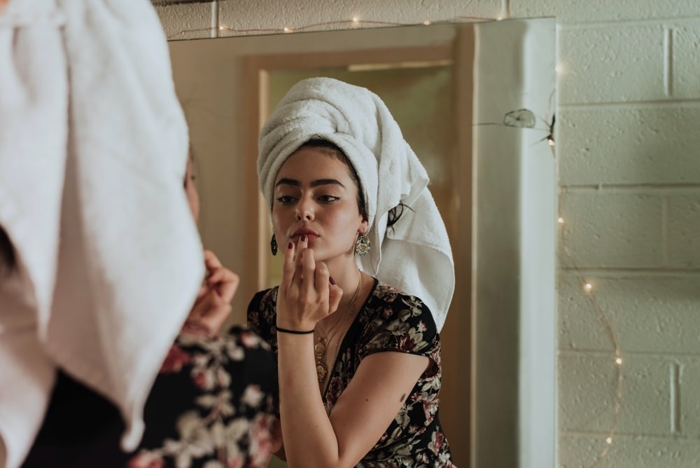 woman looking in the mirror and applying products